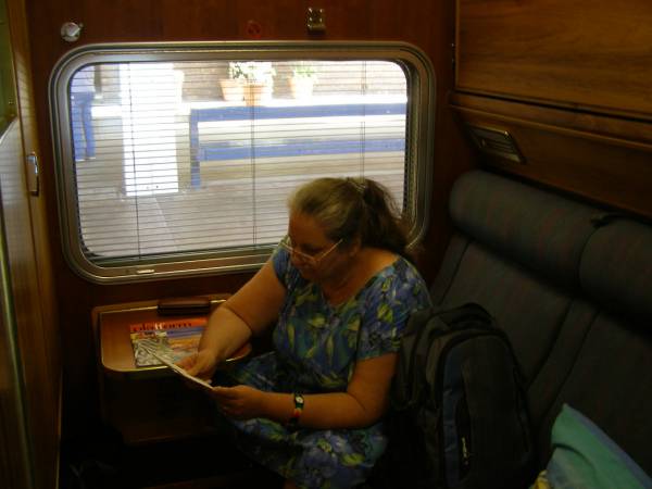 Kerry reading the information leaflet,  | in our cabin of the  | Indian Pacific,  | East Perth railway station  | 
